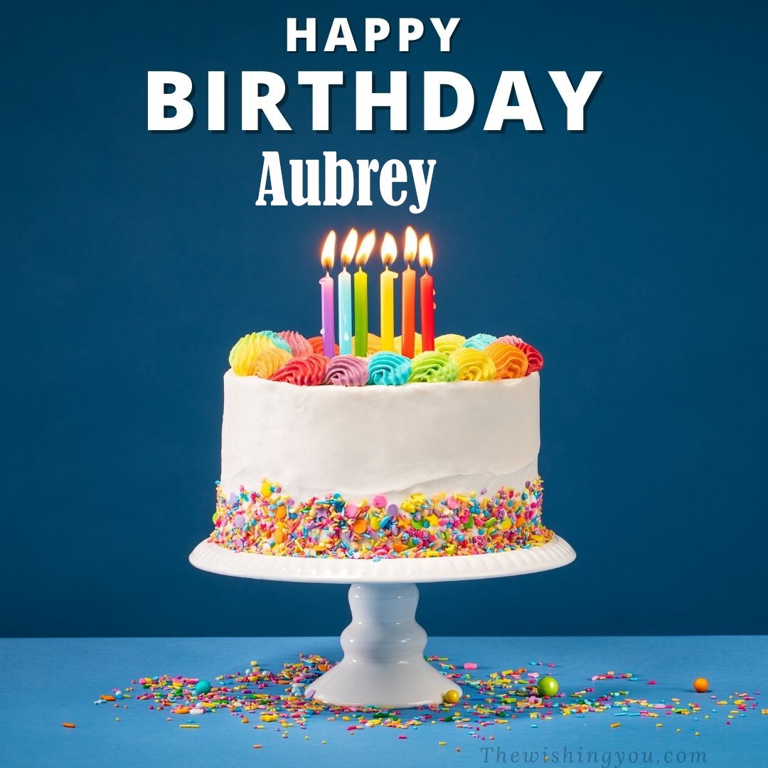 Happy birthday Aubrey written on image White cake keep on White stand and burning candles Sky background