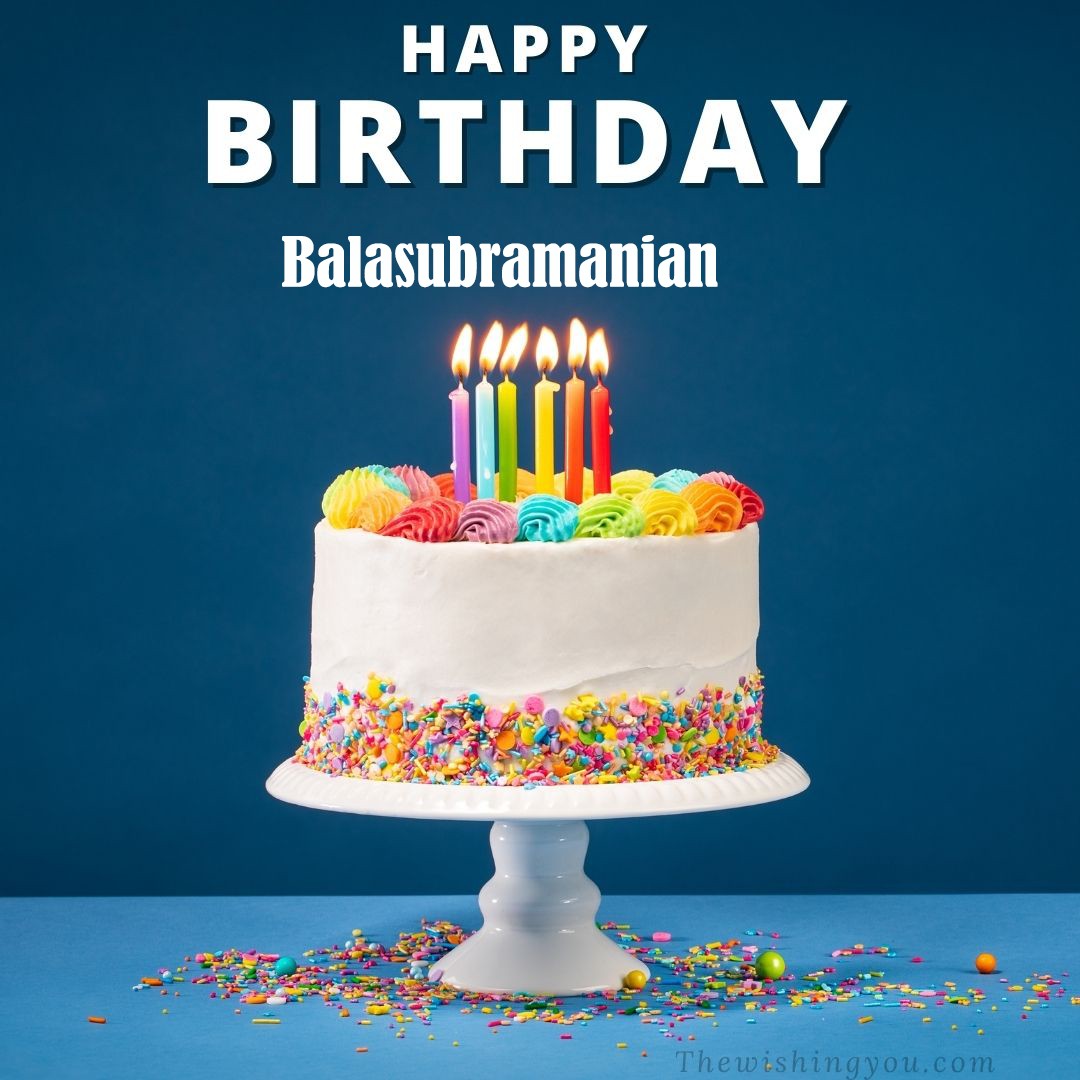 Happy Birthday Balasubramanian written on image White cake keep on White stand and burning candles Sky background