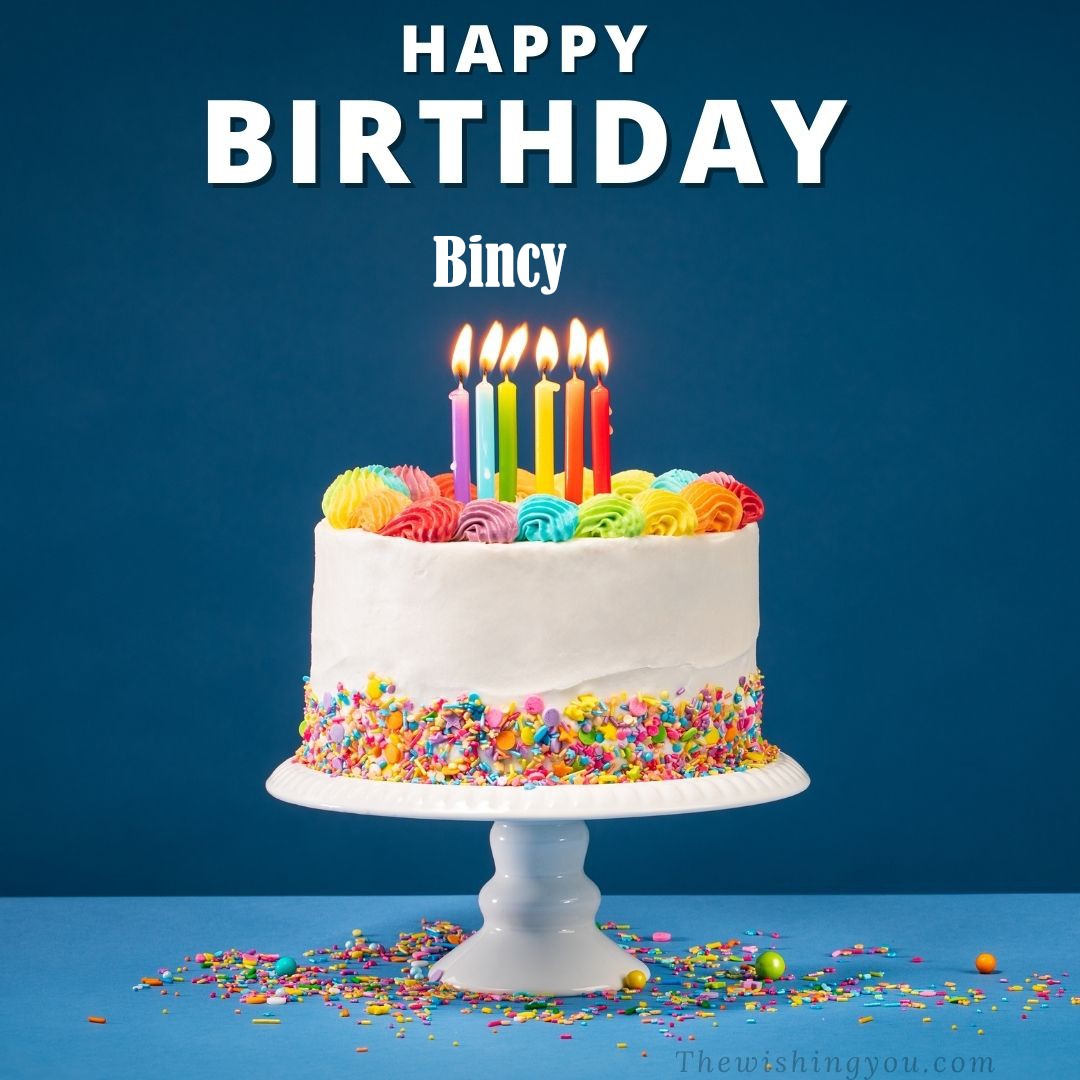 Happy Birthday Bincy written on image White cake keep on White stand and burning candles Sky background